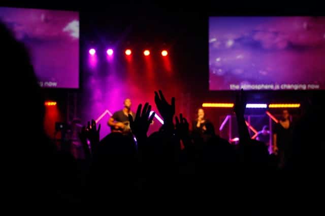 Raised hands toward a worship band on stage