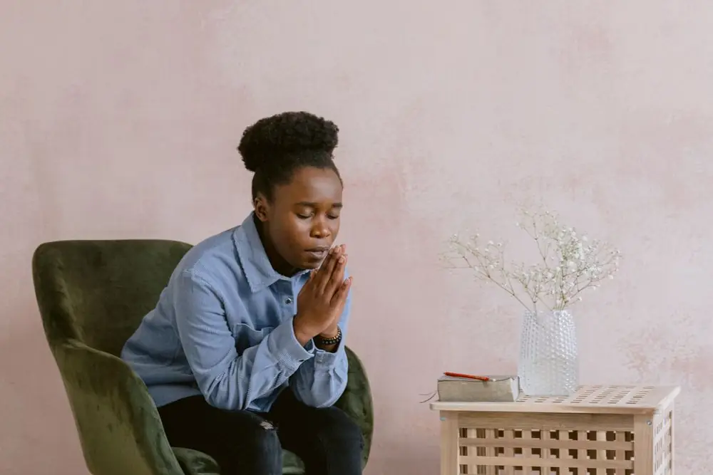 Femme afro-américaine en prière, assise près d'une Bible